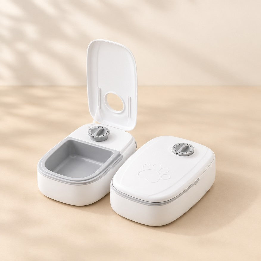 Two white automatic timer pet feeders with gray trays, one open and one closed.